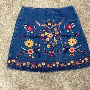 Cute denim mini skirt with stitched flower detailing.